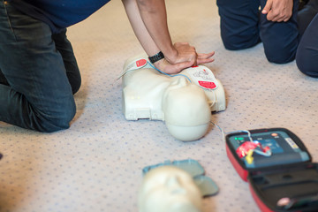 CPR training using and an AED and bag mask valve on an adult training manikin.  First aid cardiopulmonary resuscitation course using automated external defibrillator device, AED.