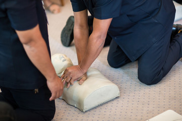 CPR training using and an AED and bag mask valve on an adult training manikin. First aid cardiopulmonary resuscitation course using automated external defibrillator device, AED.