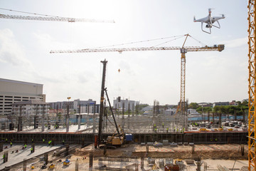 Fototapeta na wymiar Drone over construction site. video surveillance or industrial inspection. drone copter flying with digital camera.Drone with high resolution digital camera. Flying camera take a photo and video.