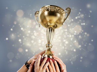 Hands holding golden trophy on light background