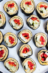 Vegan sushi rolls with chickpea hummus, cucumbers, nori seaweed, red bell pepper and avocado inside. Healthy vegetarian lunch or dinner with vegetables.