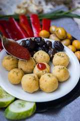 Woman hands adds tomato sauce to buddha bowl with chickpea falafel balls, tomato sauce, olives, cucumbers, red pepper. Vegan vegetables lunch, vegetarian dinner, healthy dietary food