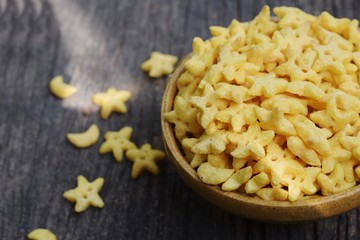 star and moon cornflakes bowl on rustic wood background with milk and spoon, breakfast concept 