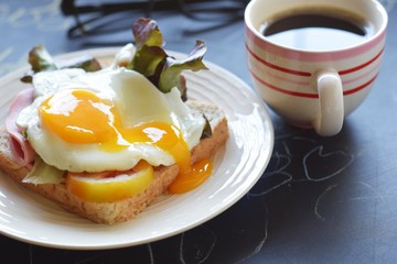 sandwich runny sunny side up egg ham with black coffee and glasses on blackboard background, brain boost breakfast concept
