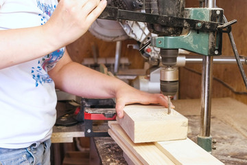 Worker drills holes in wooden templates. Manufacture of wooden toys. Close-up hands.