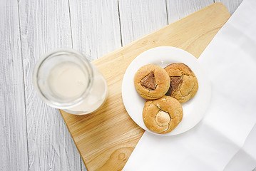 Freshly baked homemade soft cookies with bottle of milk on white wooden table