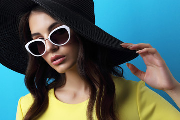 Fashion portrait of young woman wearing hat and sunglasses.