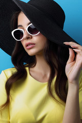 Fashion portrait of young woman wearing hat and sunglasses.