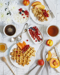 Healthy breakfast with corn waffles, fresh berries and nectarines (peaches), cottage cheese, honey, tea and coffee