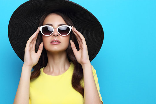 Fashion portrait of young woman wearing hat and sunglasses.