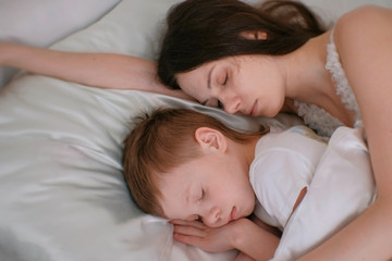 Fototapeta na wymiar Mom and son sleeping together. Mom hugging her son.