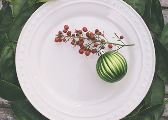 Rustic Christmas table setting with green ornament and red berries