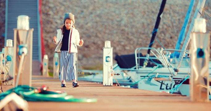 Girl child strolls along the marina for boats and boats