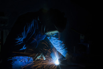 Industrial Worker in dark at the factory welding closeup