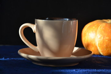 Pumpkin spiced latte or coffee in cup, dry leaves, gifts on dark blue table. Autumn or winter hot drink. Space for text, top view, copy space