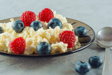 Cottage cheese with fresh raspberries and blueberries in a plate for a healthy breakfast with ripe berries. A natural healthy product.