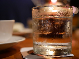 A glass of water with ice on a dinning table with candle light