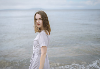 Woman in dress enjoys a walking near the sea shore.