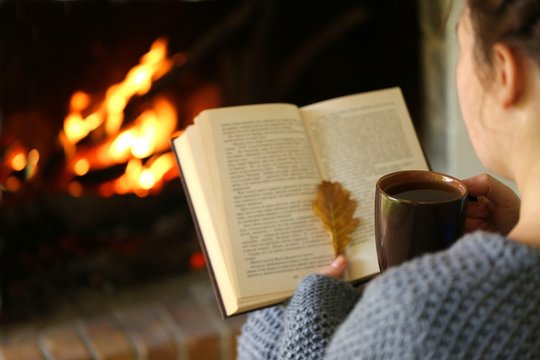 Autumn reading. Girl with a book and a cup of tea near the fireplace.Autumn books.Cozy autumn mood. Autumn time.