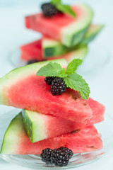 Watermelon sliced pie with blackberries and mint leaf on blue pastel background.