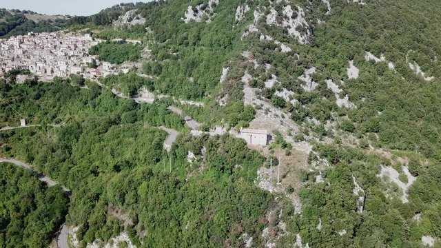 Aerial view of Cervara from far.
A small rural curch in foreground and the Ancient italian medieval village perched on a rock spur, with his ruined fortress at the top in far
