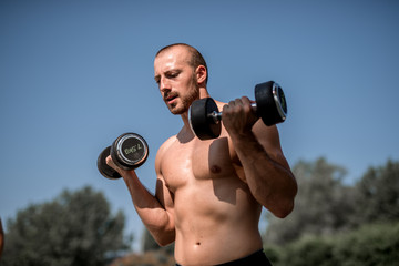 Fototapeta na wymiar Man outdoors raises weights