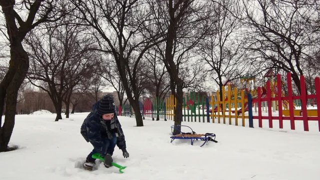 HD Cheerful boy is playing in the snow with children's shovel