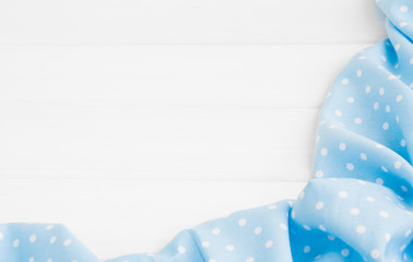 Obraz premium Light blue polka dots folded tablecloth over bleached wooden table. Top view image. Copyspace for your text.