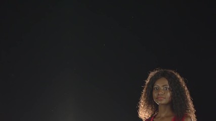 Models walk and look into the distance. Black background. Slow motion