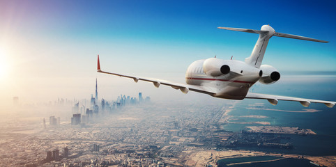 Luxury private jetliner flying above Dubai city, UAE.