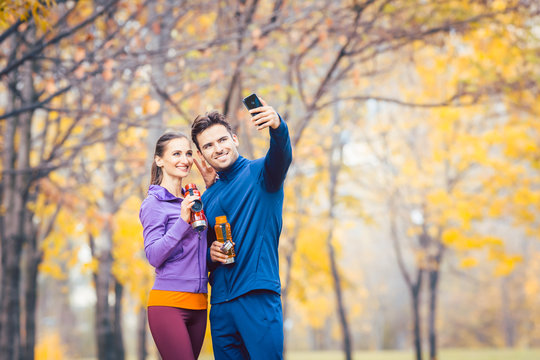 Athletic fitness couple taking selfie photo with their phone for social media