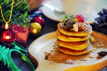 Pancake topping with berries and nut with background gift and pine cone under christmas tree, holiday party dessert.