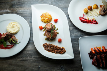 wooden table topped with white plates with different types of food in restaurant