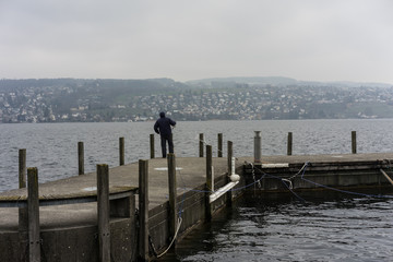 fisherman on pier in winter on a rainy day
