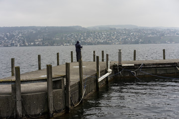 fisherman on pier in winter on a rainy day