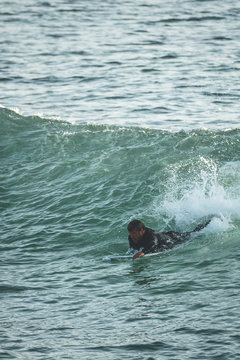 Mid aged surfer rowing a wave on a sunny summer afternoon