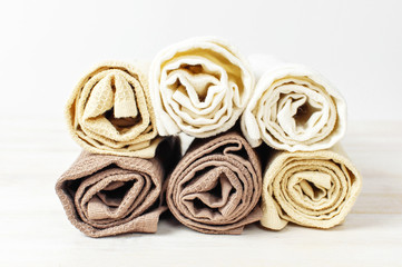 Multicolored clean towels on a light wooden background with copy space. Texture of cotton, waffle towel, textiles. Towels for kitchen or Spa concept.