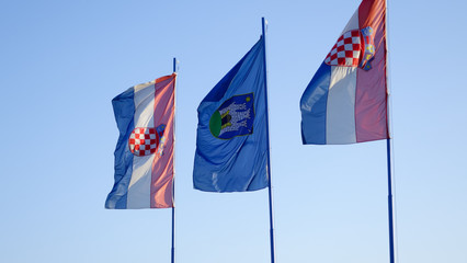 Croatian National Flags and the flag of Zagreb, blowing in the wind in front of a clear blue sky