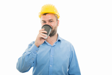 Portrait young architect with yellow helmet drinking coffee