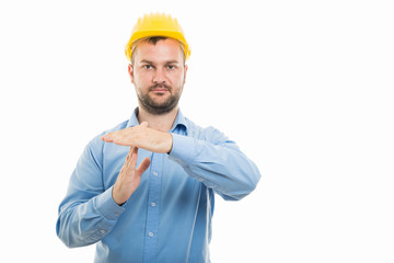 Young architect with yellow helmet showing time out gesture