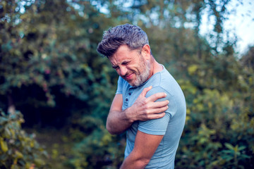 People, healthcare and problem concept - unhappy man suffering from neck or shoulder pain outdoor
