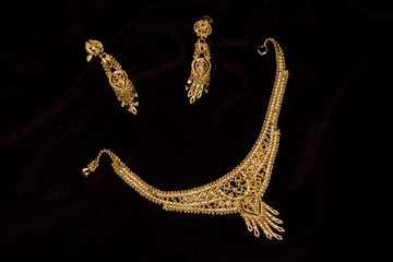 Modern golden necklace on a dark pattern