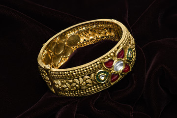 Golden bracelet on a dark pattern