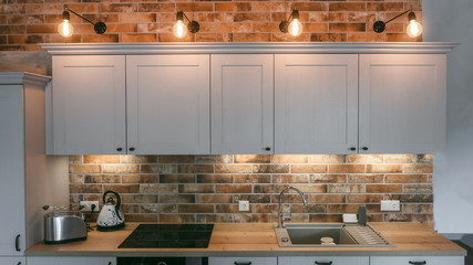 Modern kitchen with vintage lamps and a brick wall