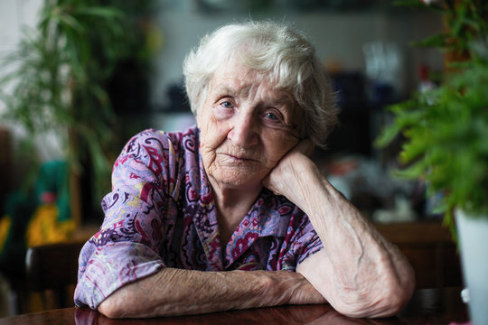 Portrait of an elderly woman sitting in a room at the table.