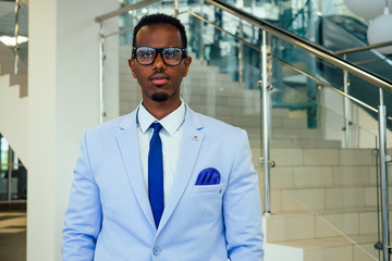 fashionable and successful African businessman American handsome man in a stylish luxury suit posing on the street business center office skyscraper background fashion model