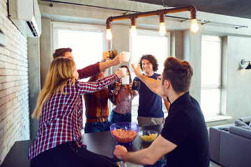 Friends raised their hands upwards with cup inside the room.