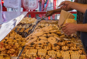 Salesmen in a market put cookies in paper bags