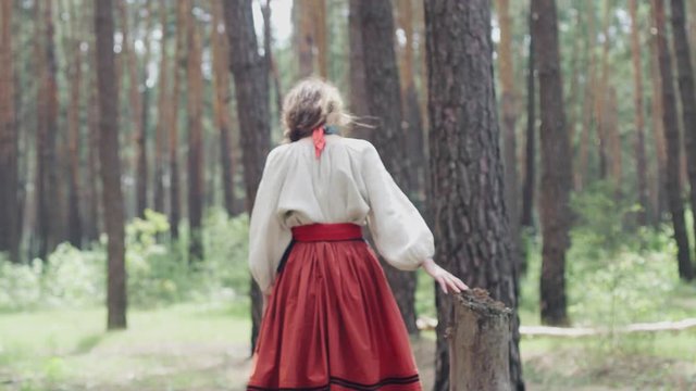 A Ukrainian girl in national clothes walks through the forest, good weather, a thoughtful positive mood