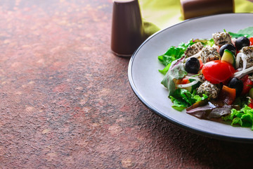 Plate with delicious fresh salad on color table